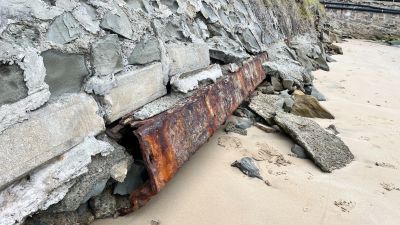 Deteriorating seawall with rusty metal bar